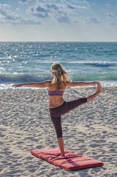 woman facing the ocean doing yoga