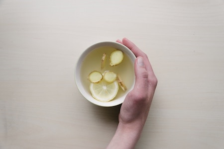 a woman's hand holding a cup of ginger tea