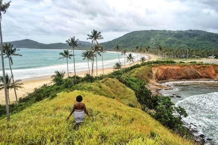 a woman walking on a small ridge overlooking
beaches on both sides
