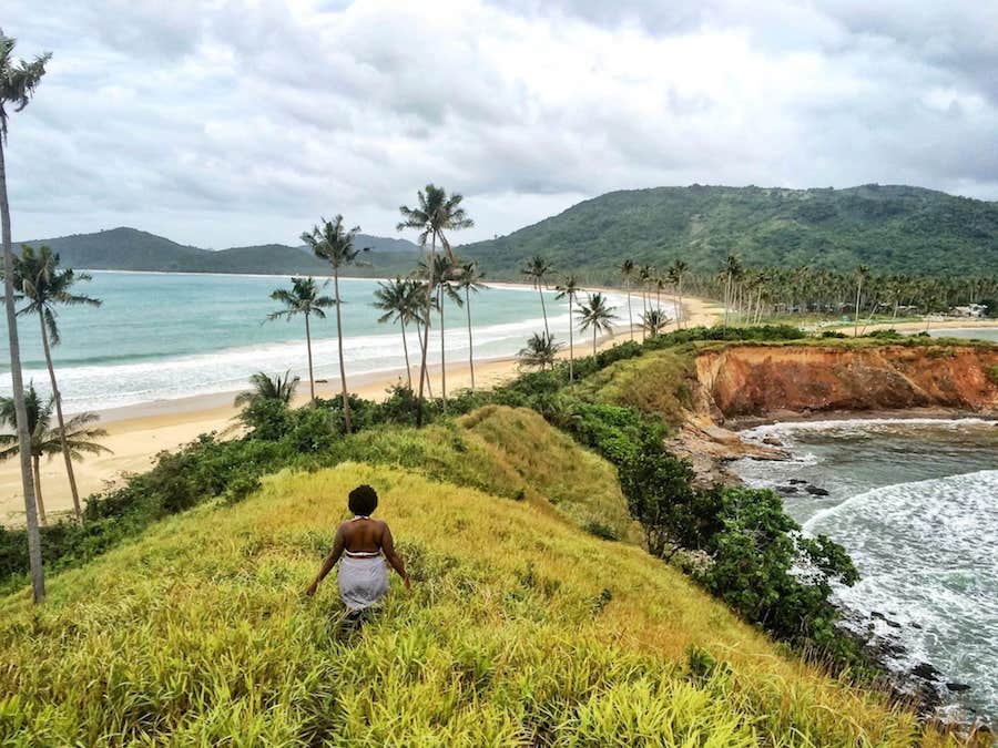 a woman walking on a small ridge overlooking beaches on both sides